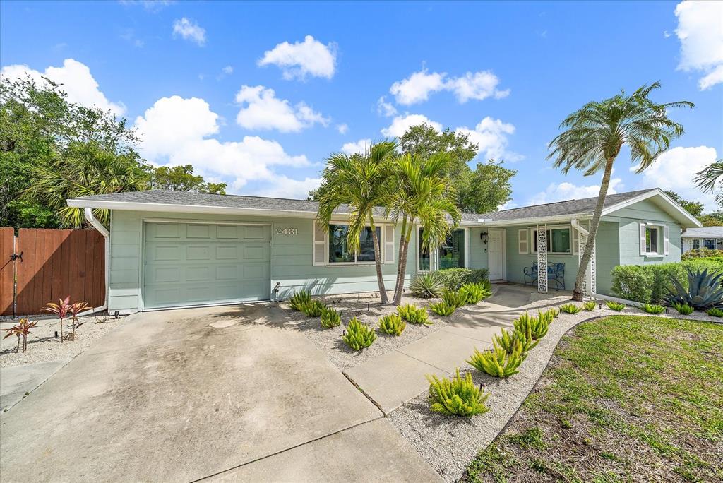 A light green single-story house features a concrete driveway, a garage, and landscaped front yard — 2431 BISPHAM ROAD, SARASOTA, FL