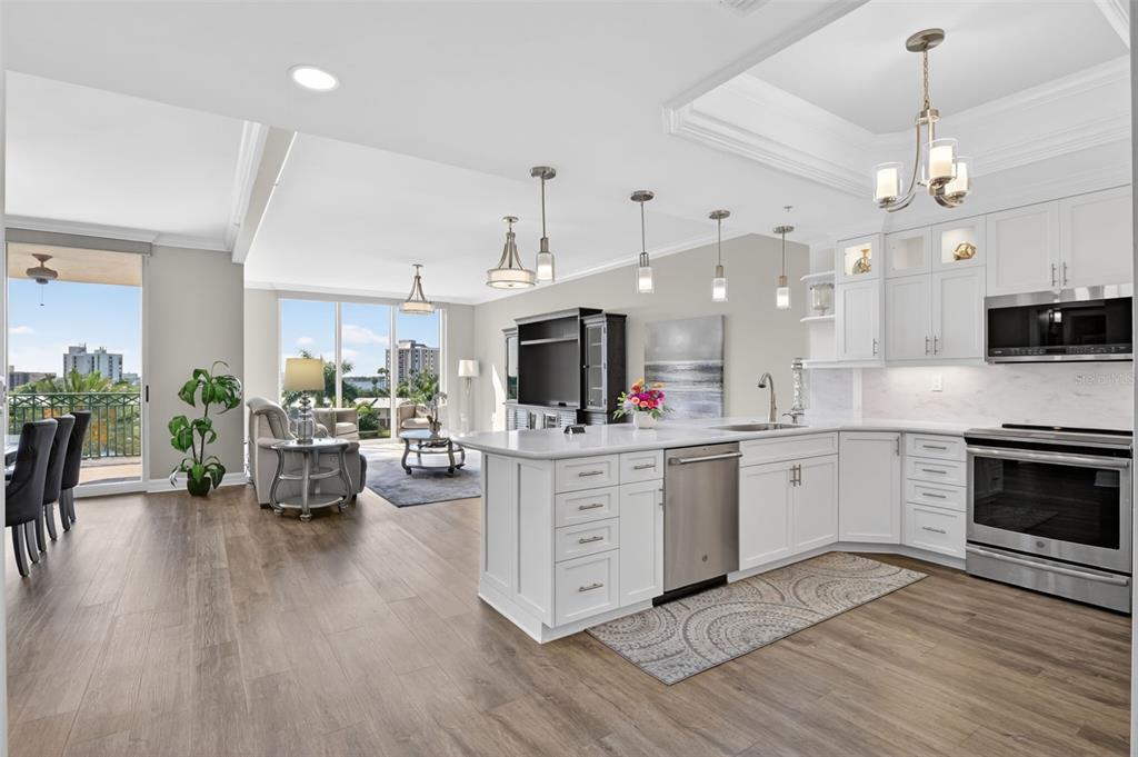 A bright, open-concept kitchen and living area with white cabinetry, stainless appliances, and balcony views — 3426 HANCOCK BRIDGE PARKWAY UNIT 503, NORTH FORT MYERS, FL