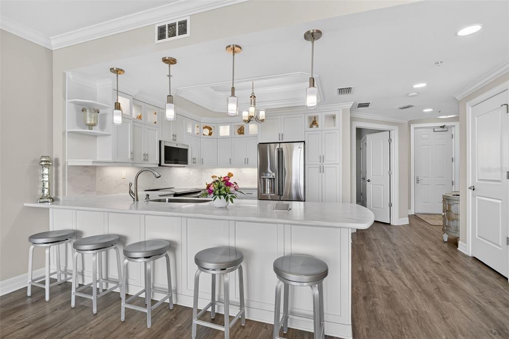 A modern kitchen features white cabinetry, a marble-topped island with bar stools, and stainless appliances — 3426 HANCOCK BRIDGE PARKWAY UNIT 503, NORTH FORT MYERS, FL