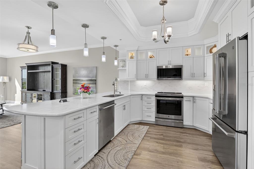 A modern kitchen features white cabinetry, stainless steel appliances, a large island, and wood flooring — 3426 HANCOCK BRIDGE PARKWAY UNIT 503, NORTH FORT MYERS, FL