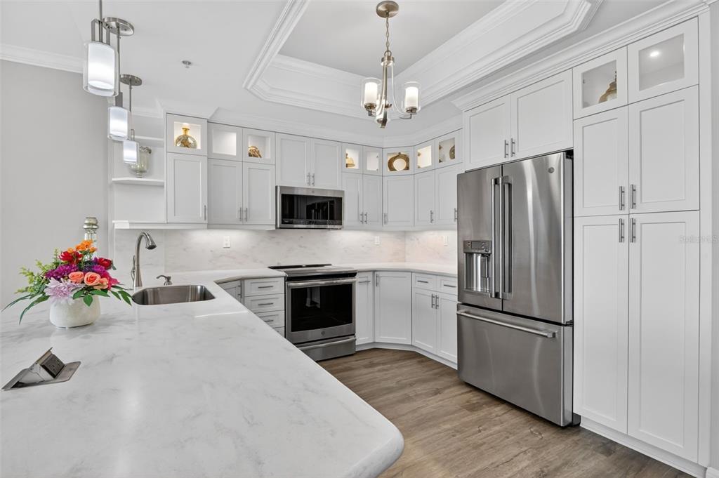 A modern kitchen features white cabinetry, stainless steel appliances, and a large marble-topped island — 3426 HANCOCK BRIDGE PARKWAY UNIT 503, NORTH FORT MYERS, FL