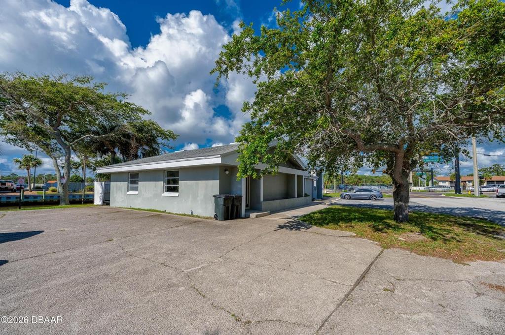 A gray single-story building with a concrete parking lot and a large tree — 2763 S RIDGEWOOD AVENUE, SOUTH DAYTONA, FL