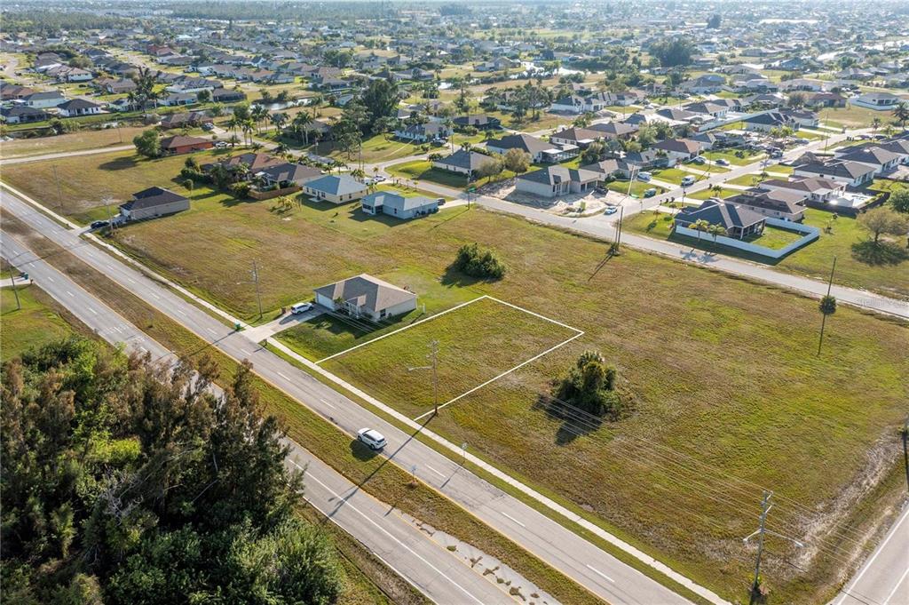 An aerial view shows a vacant rectangular lot outlined in white next to a house — 10 EL DORADO BOULEVARD S, CAPE CORAL, FL