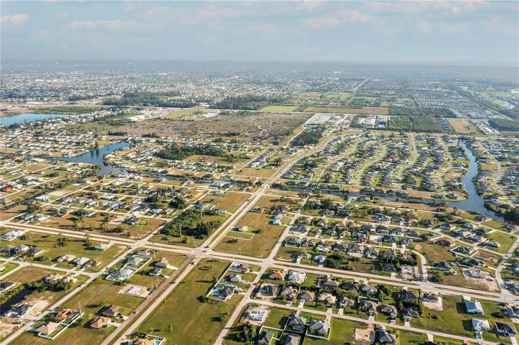 An aerial view shows a residential neighborhood with scattered houses, canals, and undeveloped land — 10 EL DORADO BOULEVARD S, CAPE CORAL, FL