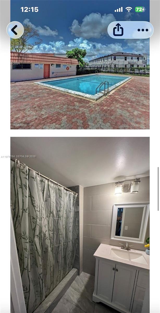 A kitchen with dark countertops, wooden cabinets, and white appliances opens to an entryway — 851 NE 207th Ter # 103, Miami FL 33179, MIAMI, FL