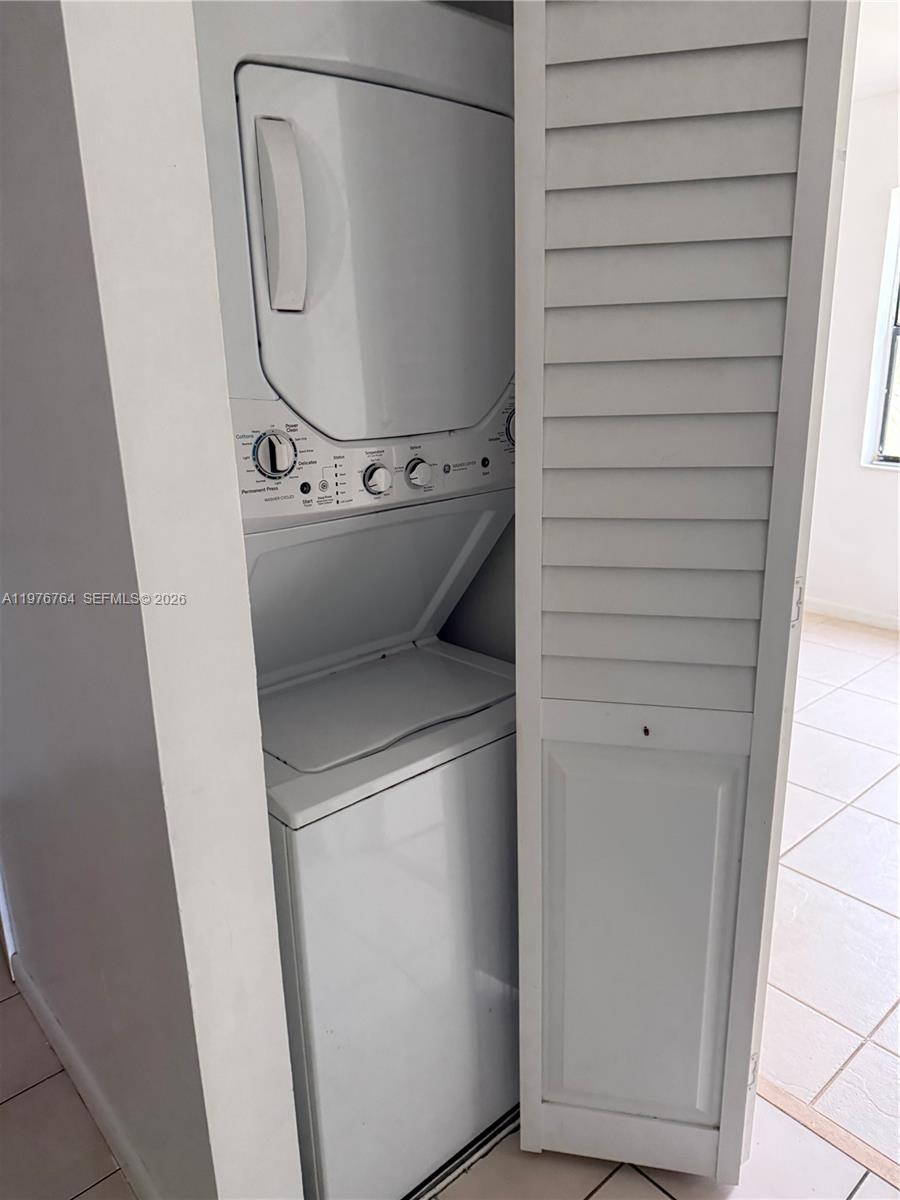 A tiled entryway leads to a white door with a laundry closet on the right — 851 NE 207th Ter # 103, Miami FL 33179, MIAMI, FL