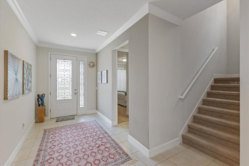 An entryway features a front door with glass panels, a patterned rug, and carpeted stairs — 7180 BEEK STREET, WINDERMERE, FL