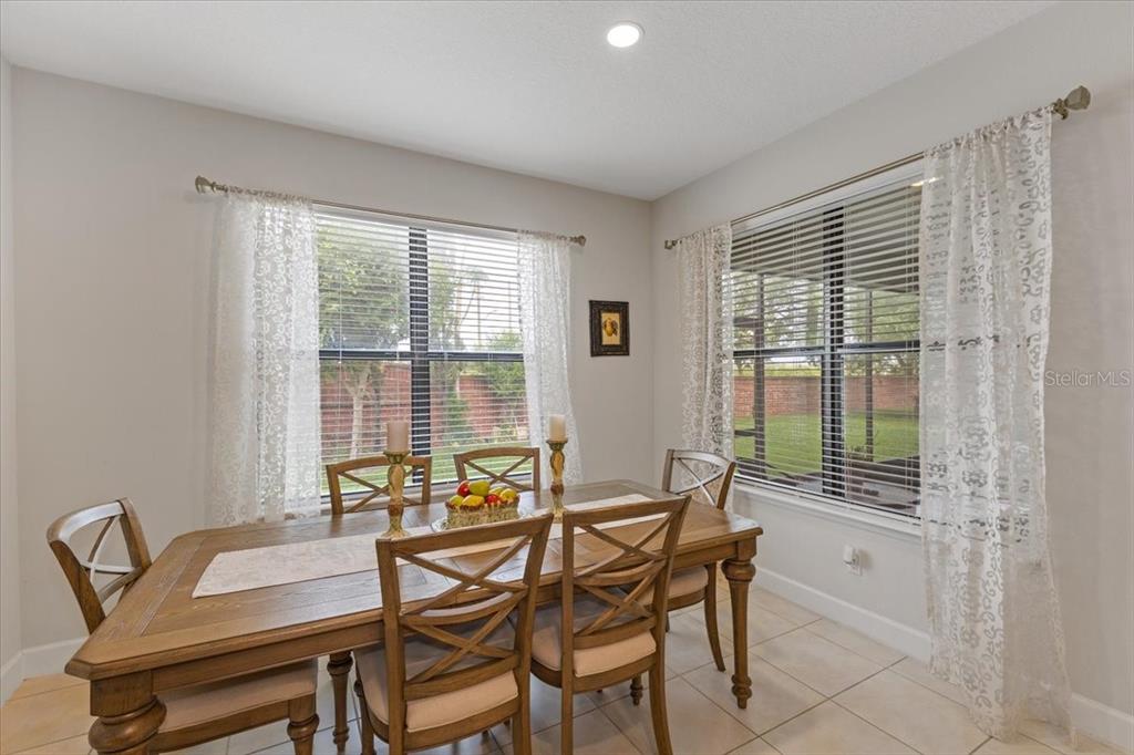 A dining room features a wooden table with six chairs, tile flooring, and two windows — 7180 BEEK STREET, WINDERMERE, FL