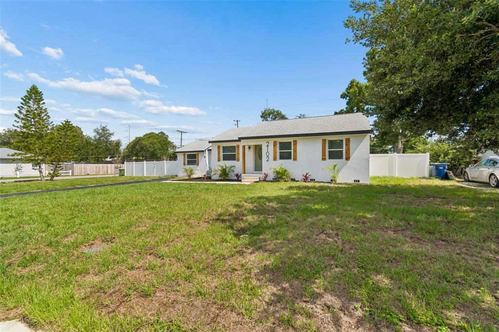 A single-story white house with a gray roof and wooden shutters sits on a lawn — 2102 W FERRIS AVENUE, TAMPA, FL