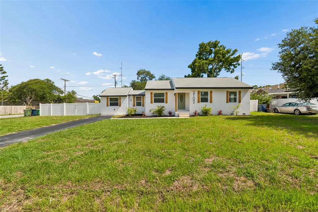 A white single-story house with a dark roof, wooden shutters, and a large front lawn — 2102 W FERRIS AVENUE, TAMPA, FL