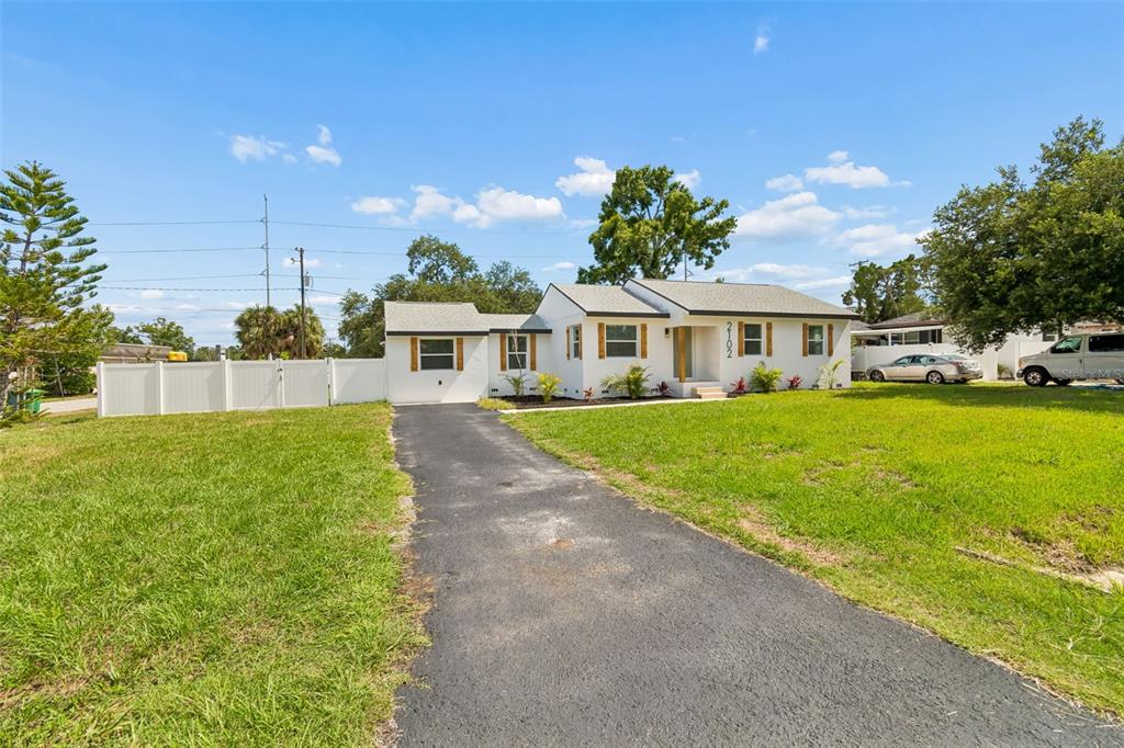 A white single-story house with a dark asphalt driveway and a white vinyl fence — 2102 W FERRIS AVENUE, TAMPA, FL
