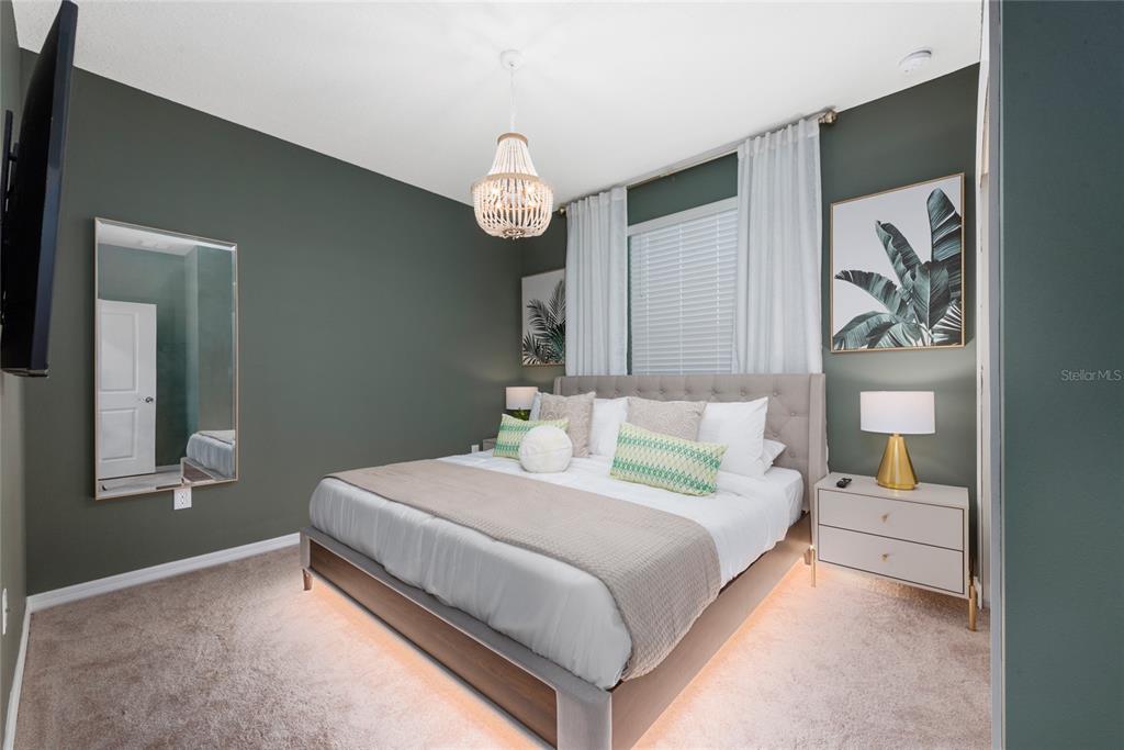 A bedroom features a tufted headboard, a beaded chandelier, and dark green accent walls — 4322 LANA AVENUE, DAVENPORT, FL