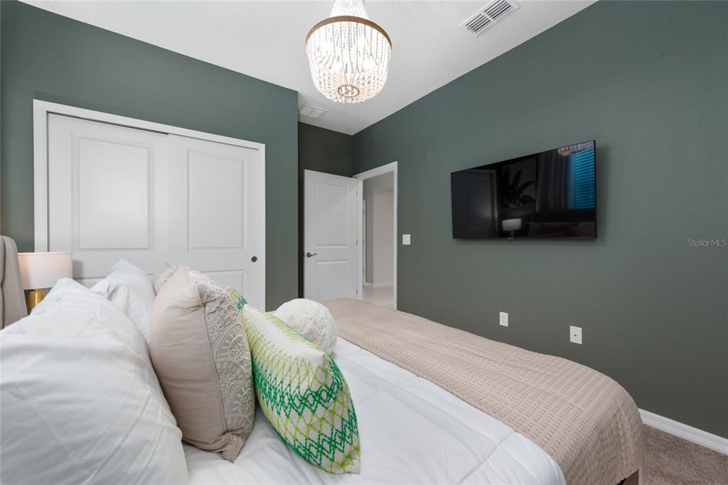A bedroom features dark green walls, a white ceiling fan, and a wall-mounted television — 4322 LANA AVENUE, DAVENPORT, FL