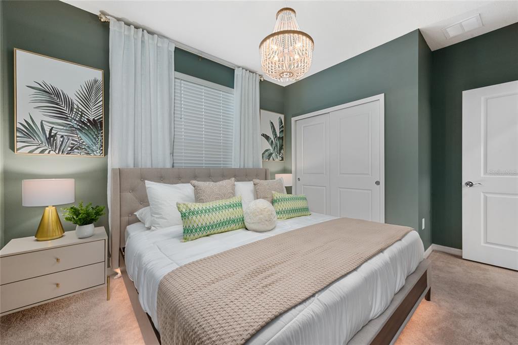 A bedroom features a tufted headboard, green walls, a beaded chandelier, and a white closet — 4322 LANA AVENUE, DAVENPORT, FL