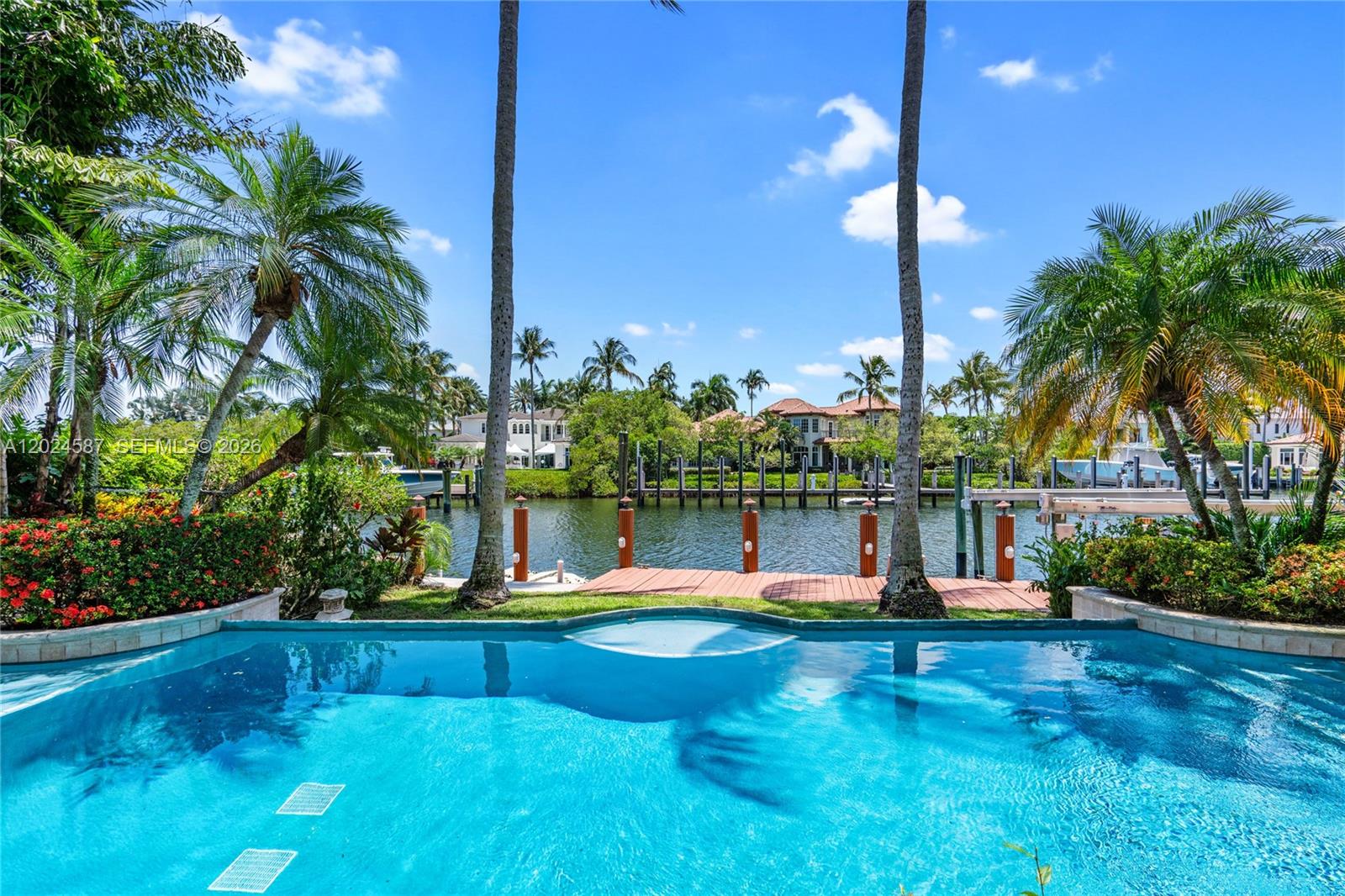 A swimming pool overlooks a wooden dock and a canal lined with palm trees — 832 Harbour Isle Place, North Palm Beach FL 33410, NORTH PALM BEACH, FL