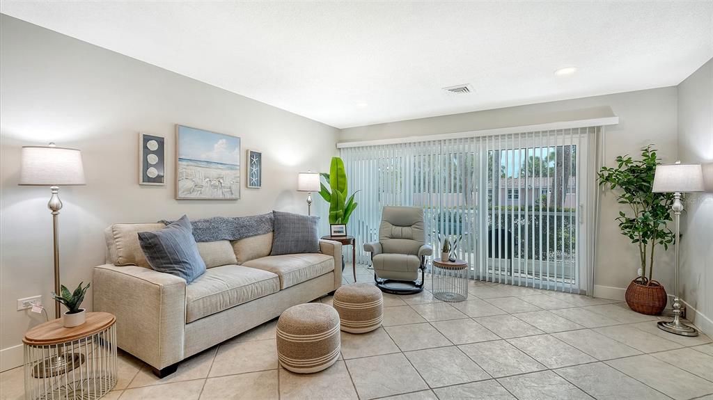 A living room features a beige sofa, a recliner, two ottomans, and tile flooring — 500 S WASHINGTON DRIVE UNIT 6A, SARASOTA, FL