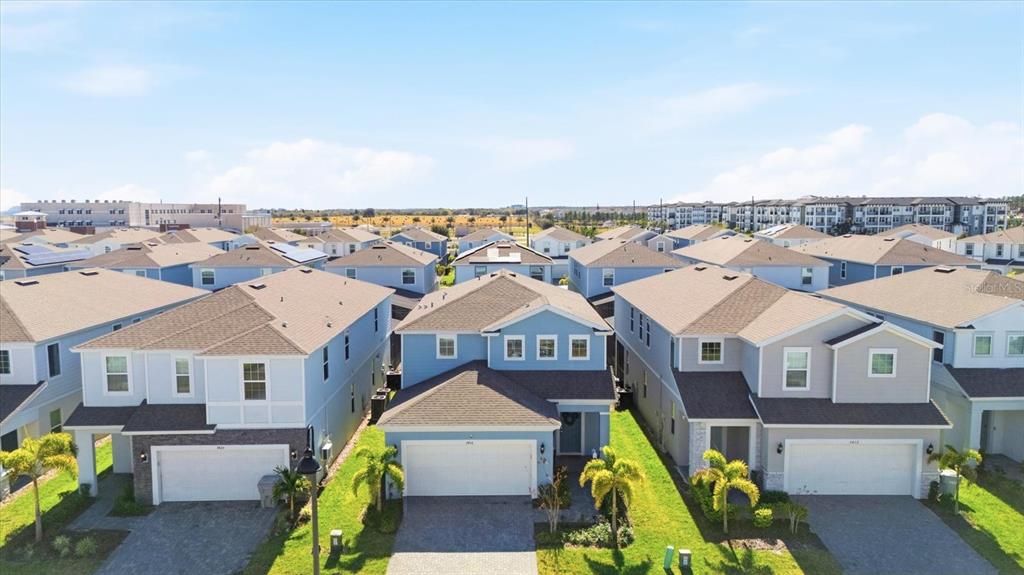 An aerial view shows three suburban houses with light blue siding and attached garages — 3416 LILAC WAY, DAVENPORT, FL