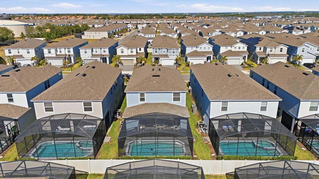 An aerial view shows several two-story houses with screened-in swimming pools in a suburban neighborhood — 3416 LILAC WAY, DAVENPORT, FL