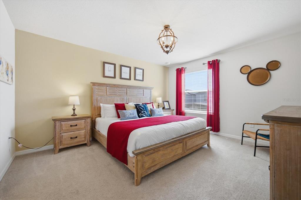 A bedroom features a wooden bed frame, red curtains, and a Mickey Mouse-shaped wall decoration — 3416 LILAC WAY, DAVENPORT, FL
