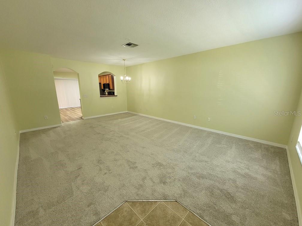 A spacious living room with light green walls, beige carpeting, and a dining area pass-through — 16414 SWAN VIEW CIRCLE UNIT 16414, ODESSA, FL
