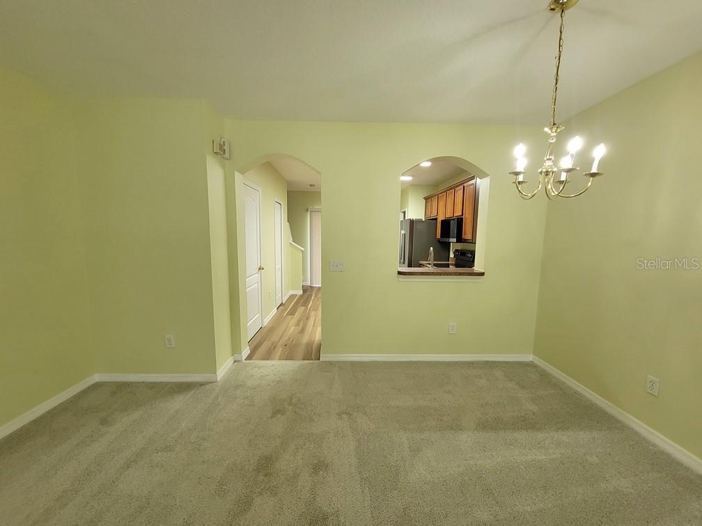 A dining area with beige carpet, light green walls, and a pass-through window to the kitchen — 16414 SWAN VIEW CIRCLE UNIT 16414, ODESSA, FL