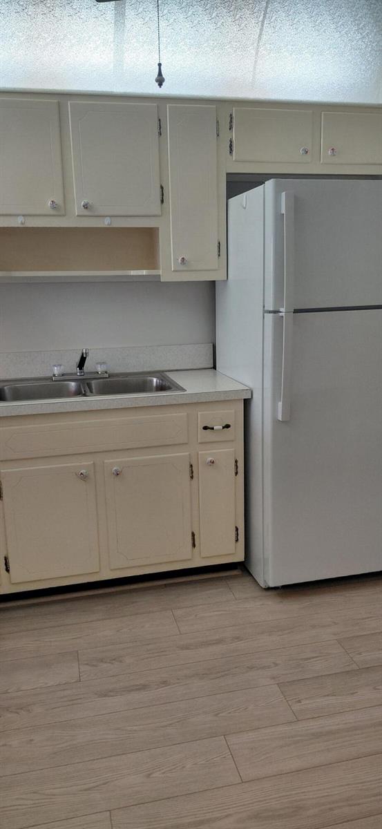 A kitchen features off-white cabinets, a stainless steel sink, and a white refrigerator — 2616 Garden Drive N # 303, FL 33461, FL