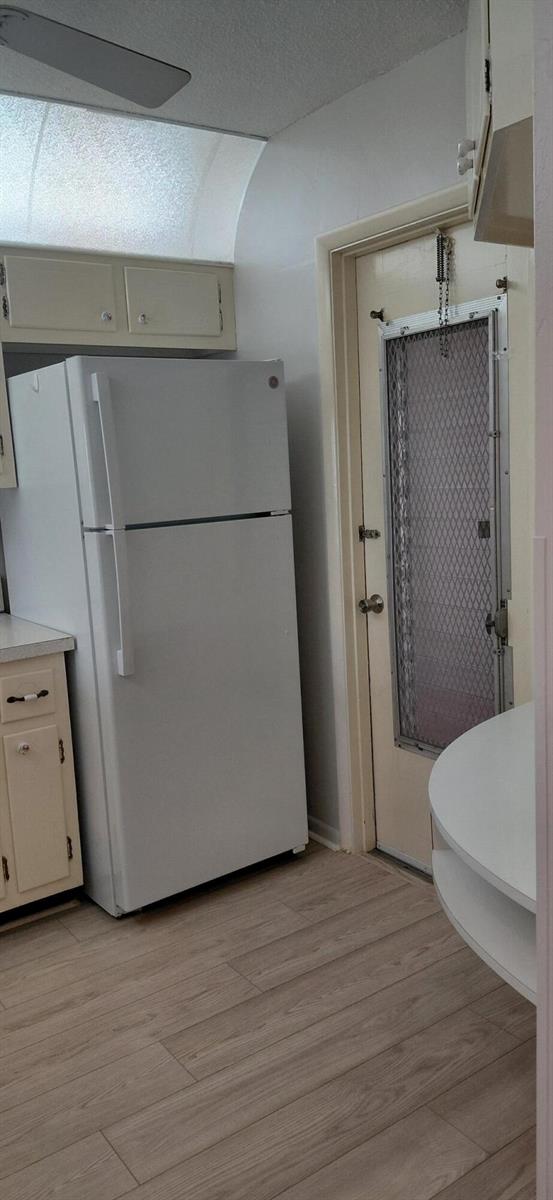 A white refrigerator stands in a kitchen with light wood-look flooring and a screen door — 2616 Garden Drive N # 303, FL 33461, FL