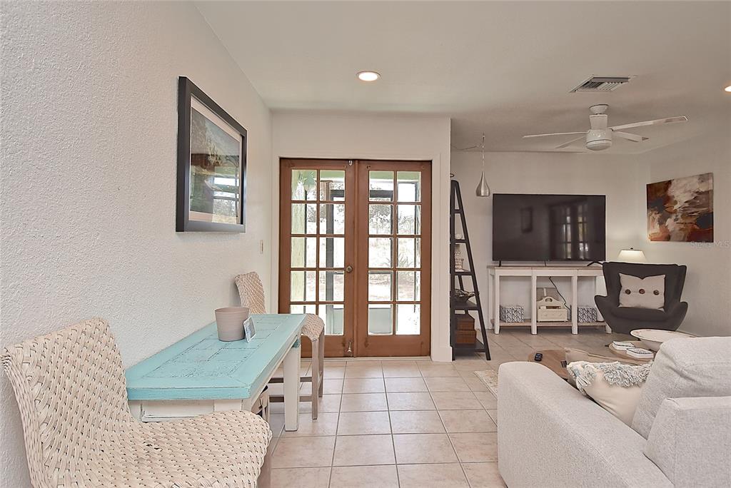 A living room features tile floors, a light blue console table, and wooden French doors — 7037 DUKE STREET, ENGLEWOOD, FL