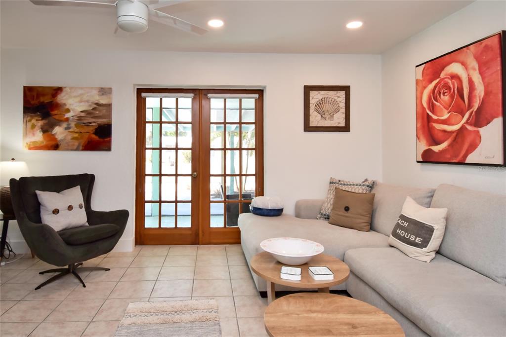 A living room features a gray sectional sofa, an armchair, and French doors leading outside — 7037 DUKE STREET, ENGLEWOOD, FL