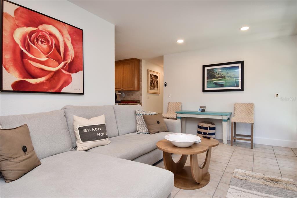 A living room features a grey sectional sofa, a round wooden coffee table, and tile flooring — 7037 DUKE STREET, ENGLEWOOD, FL