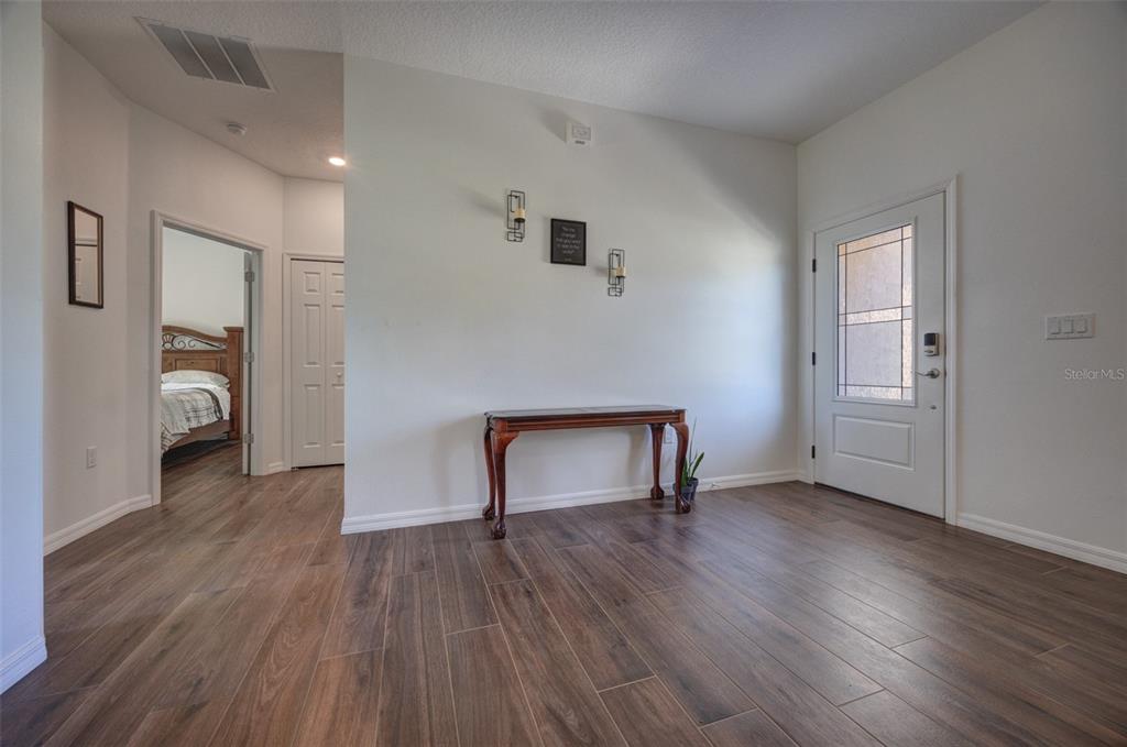An entryway features wood-look tile flooring, a console table against a wall, and a front door — 174 DOVER LN, DELAND, FL