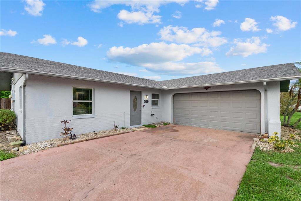 A single-story house with a gray exterior, a gray garage door, and a red concrete driveway — 519 64TH AVENUE DRIVE E, BRADENTON, FL