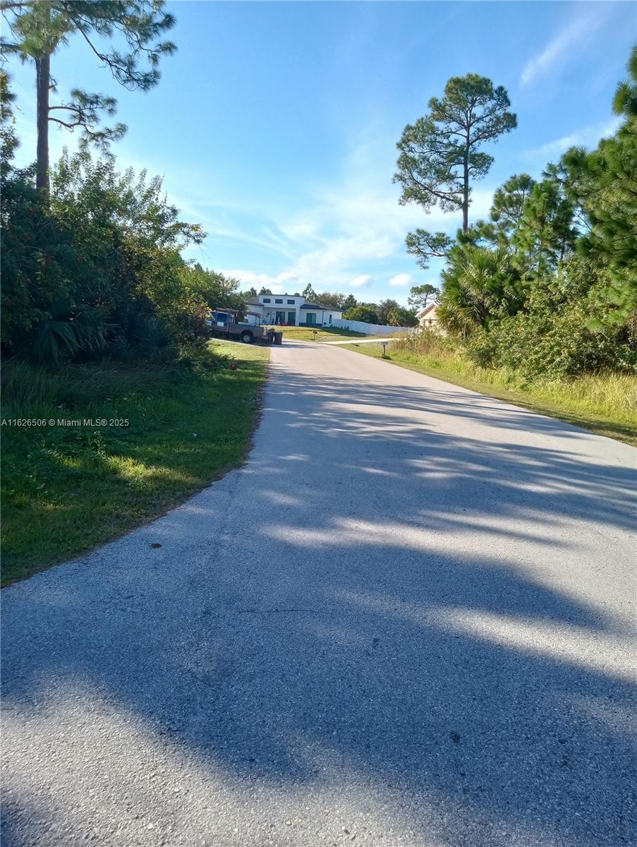 A paved road leads toward a white house surrounded by trees and vegetation — 0 Ocean Ave SW, Palm Bay FL 32908, PALM BAY, FL