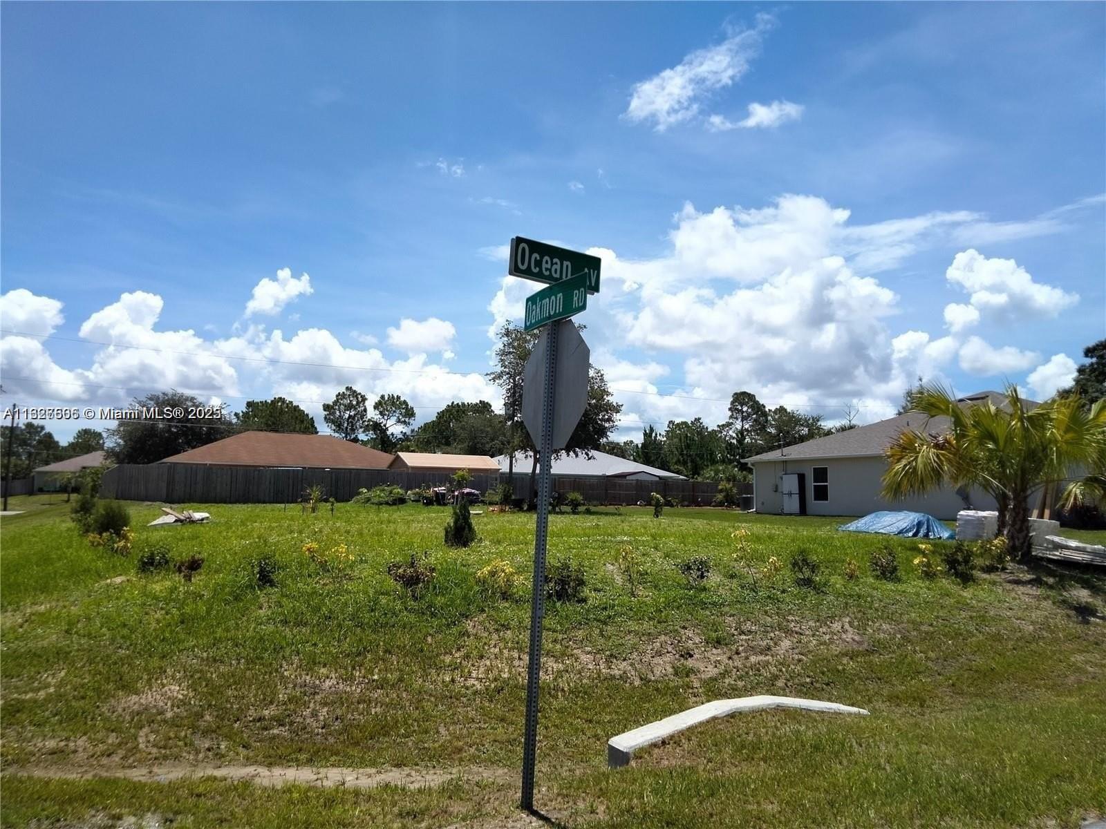 A street sign stands at the corner of a grassy vacant lot under a blue sky — 0 Ocean Ave SW, Palm Bay FL 32908, PALM BAY, FL