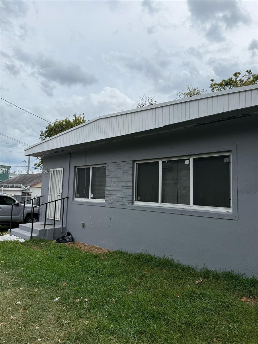 A gray exterior wall of a house features a white door and two windows — 170 NE 68th Ter, Miami FL 33138, MIAMI, FL
