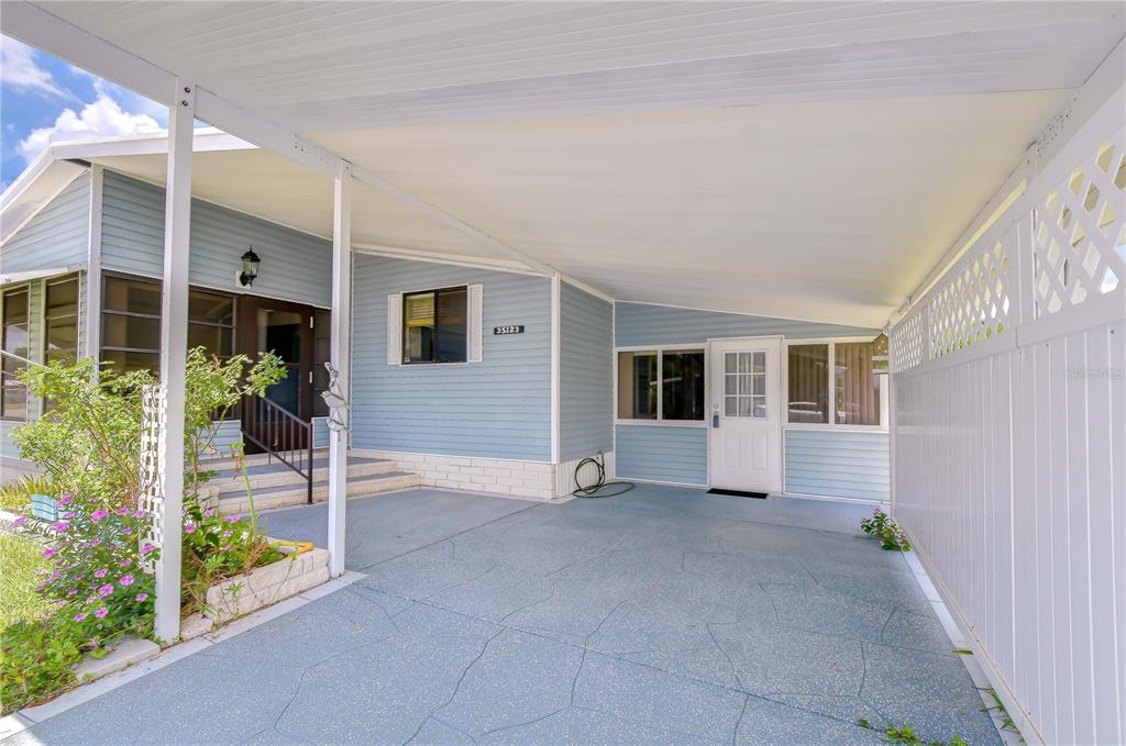 A light blue mobile home features a covered carport and a concrete driveway — 35123 COLONY HILLS DRIVE, ZEPHYRHILLS, FL