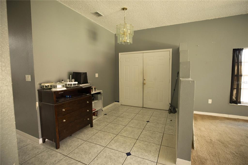 An entryway features tiled flooring, a dark wood dresser, and a double-door front entrance — 1055 UNIVERSAL REST PLACE, KISSIMMEE, FL