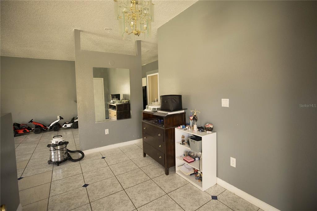 A tiled room features a dark wood dresser, a white bookshelf, and a wall mirror — 1055 UNIVERSAL REST PLACE, KISSIMMEE, FL