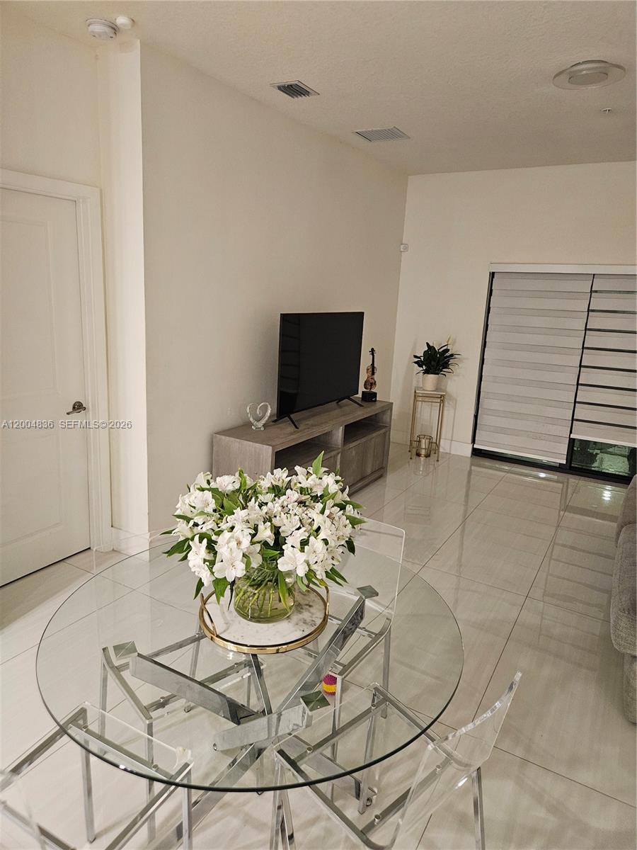 A dining area with a glass table and chairs sits in front of a living room — 8167 NW 41st St # 109, Doral FL 33166, DORAL, FL