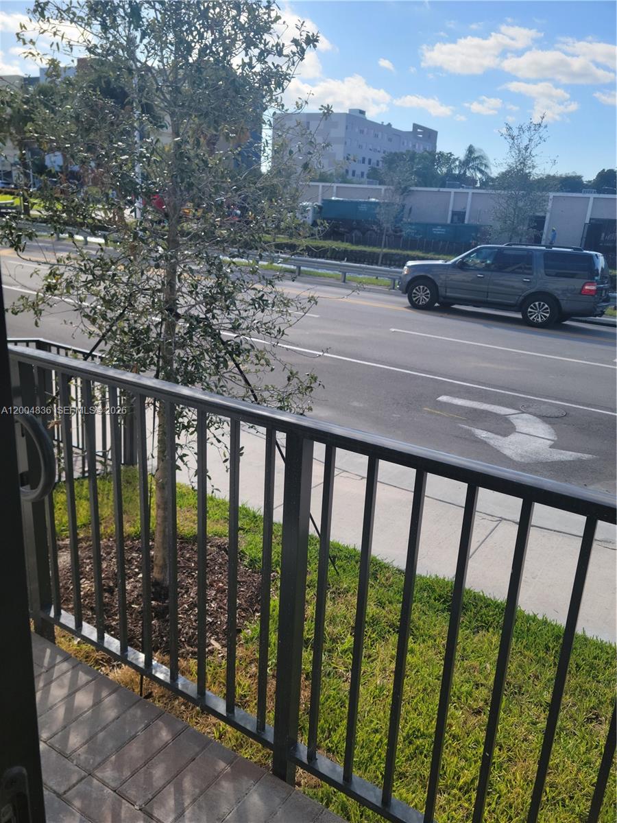 A view from a balcony overlooking a road with a car and a small tree — 8167 NW 41st St # 109, Doral FL 33166, DORAL, FL