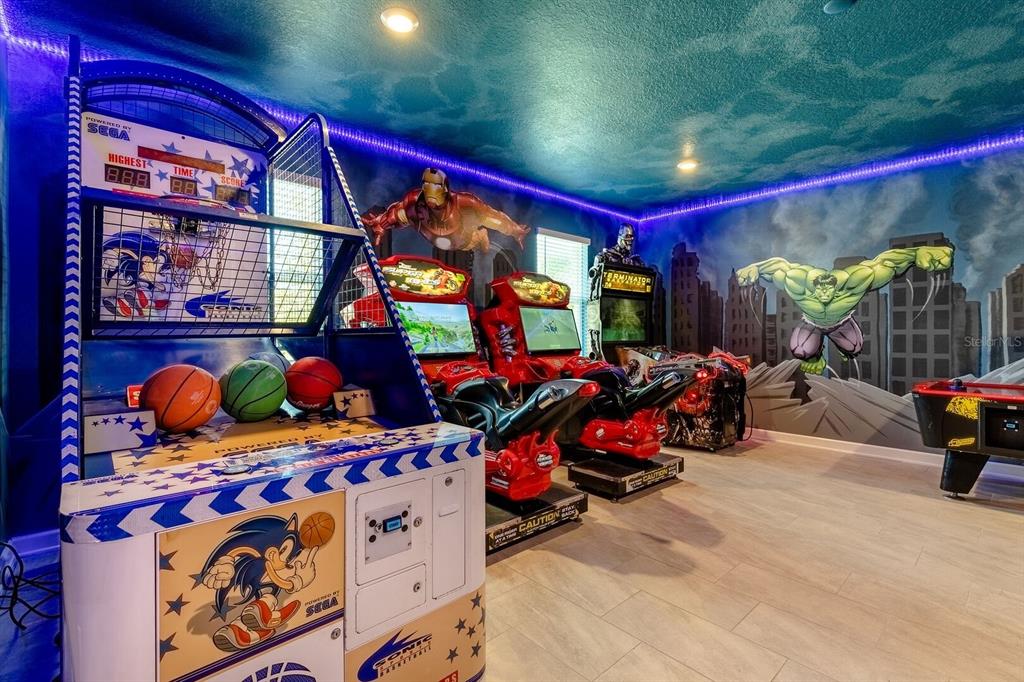 A game room features a basketball arcade machine, two racing simulators, and superhero wall murals — 9012 SOMMERSET HILLS DRIVE, DAVENPORT, FL