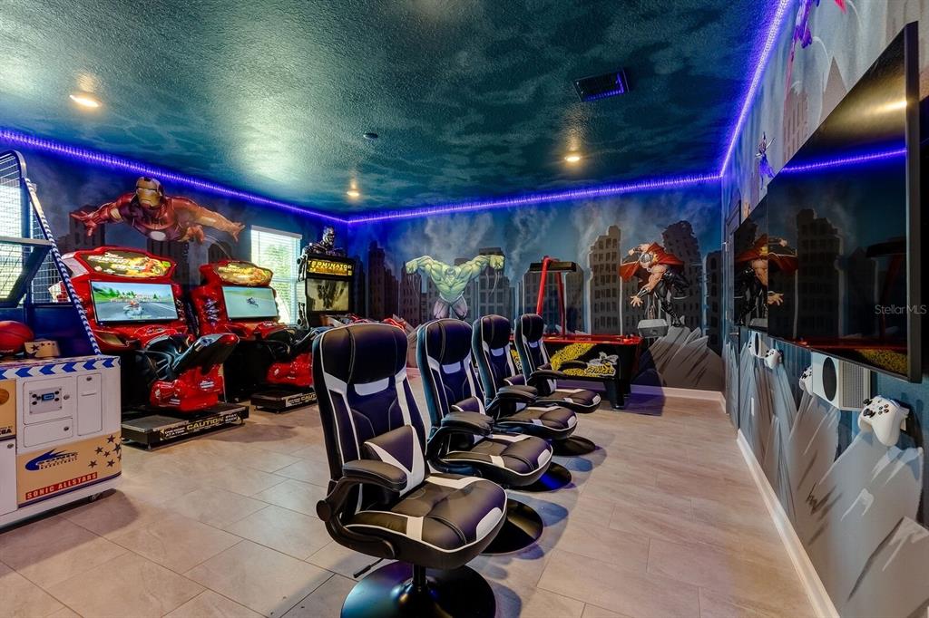 A themed game room features arcade machines, gaming chairs, wall murals, and a large television — 9012 SOMMERSET HILLS DRIVE, DAVENPORT, FL