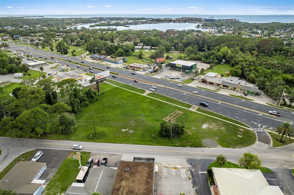 An aerial view shows a vacant grassy lot situated between a highway and a side road — 00 US HWY 19, PORT RICHEY, FL