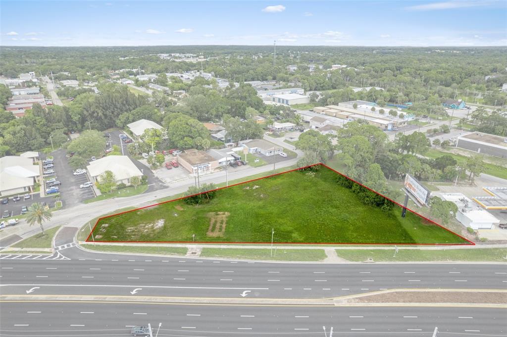 An aerial view shows a triangular, grass-covered vacant lot bordered by a multi-lane road — 00 US HWY 19, PORT RICHEY, FL