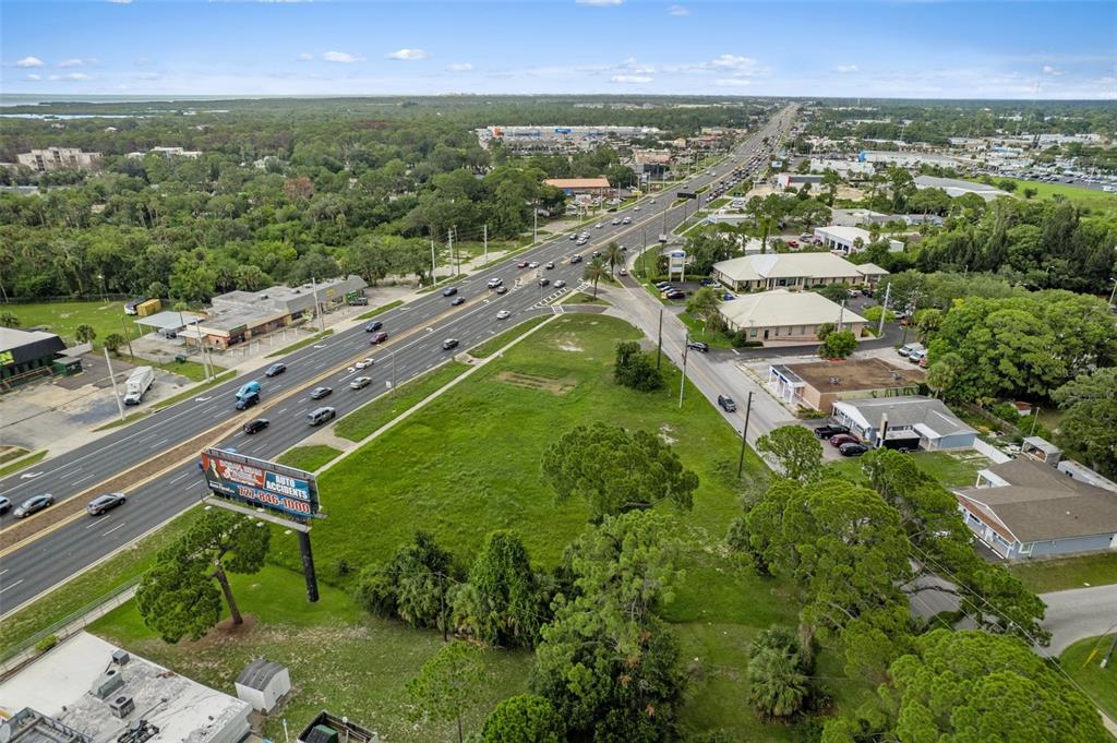 An aerial view shows a large vacant grassy lot situated between a highway and commercial buildings — 00 US HWY 19, PORT RICHEY, FL