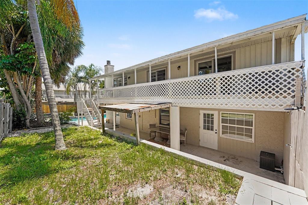 A backyard swimming pool sits next to a light-colored house with palm trees and fencing — 4941 CARDINAL TRAIL, PALM HARBOR, FL