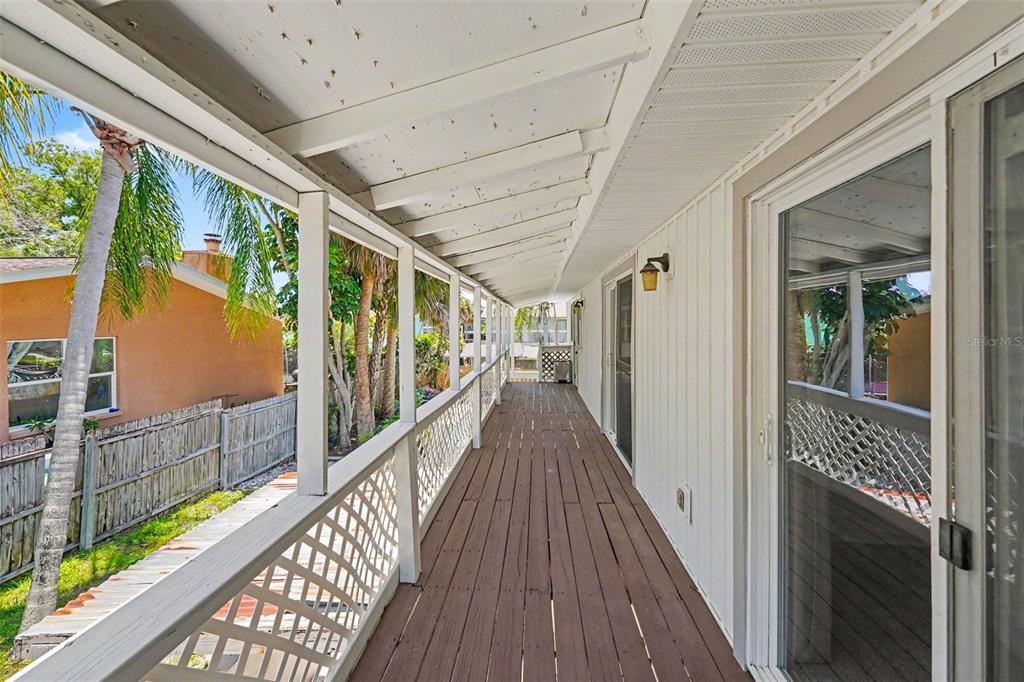 A backyard swimming pool sits in front of a two-story house with a wooden deck — 4941 CARDINAL TRAIL, PALM HARBOR, FL
