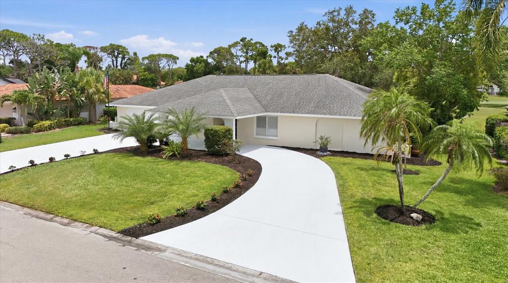 A single-story house with a light-colored exterior, a gray shingled roof, and a curved driveway — 3900 TORREY PINES BOULEVARD, SARASOTA, FL