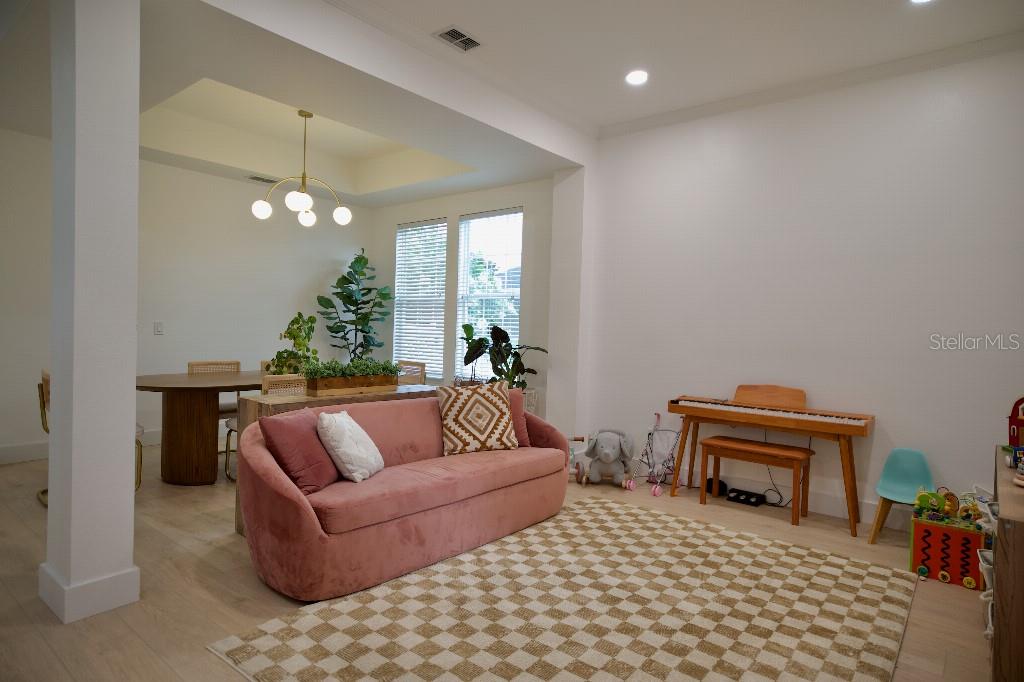A living room features a pink curved sofa, a checkered rug, and a wooden piano — 311 REEVES STREET, KISSIMMEE, FL