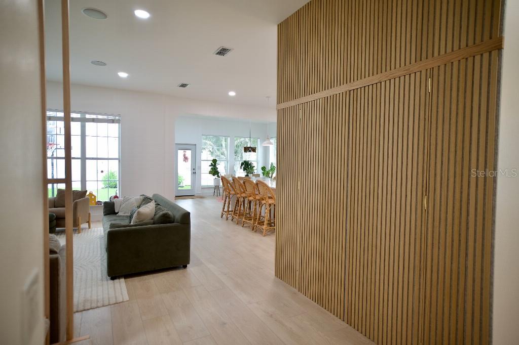 A living room with light wood flooring and a large vertical-slat wood accent wall — 311 REEVES STREET, KISSIMMEE, FL